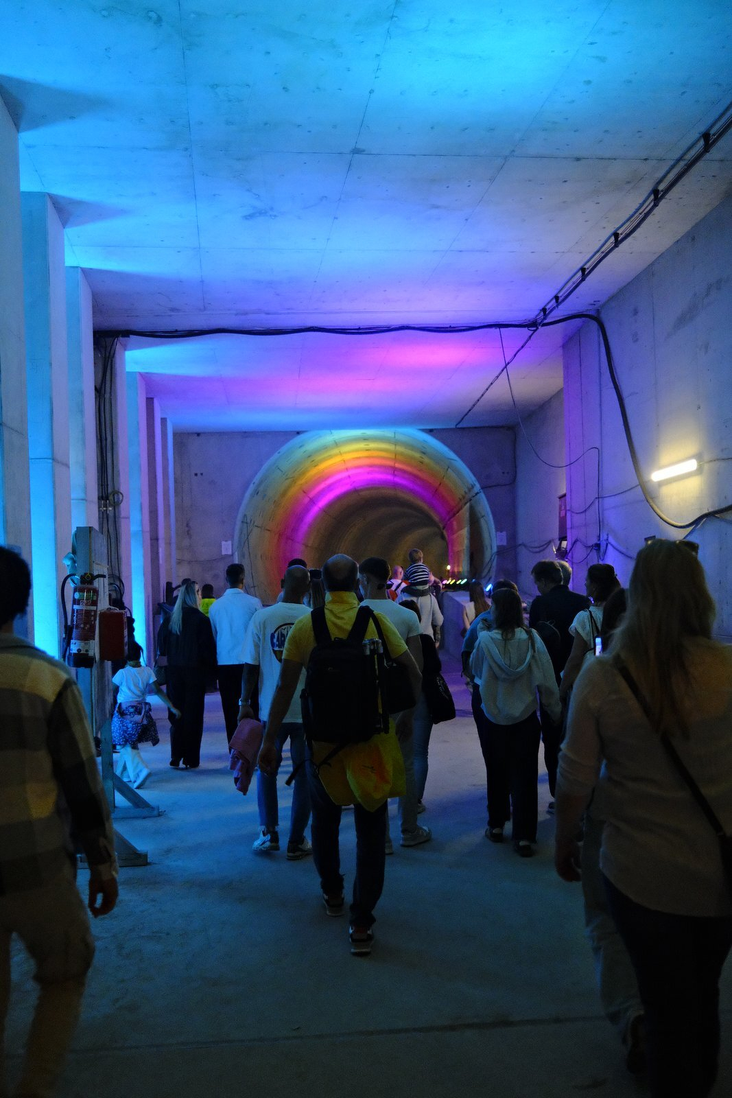 Visitors walking through a tunnel lit in rainbow colours