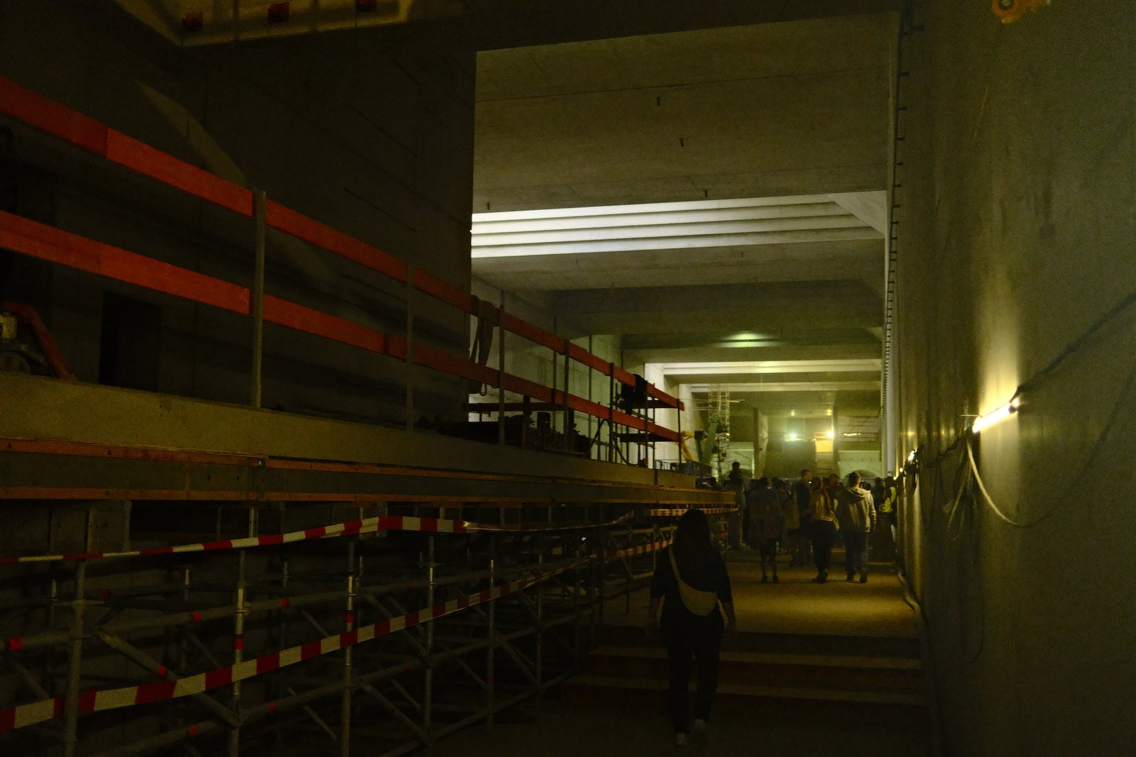 Long underground station hall with scaffolding, visitors in the distance