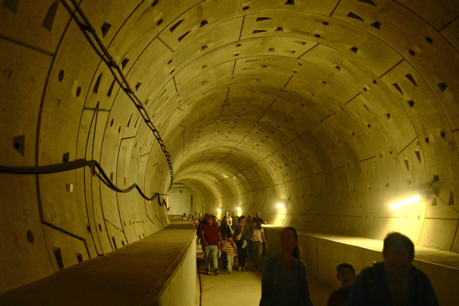 Curved tunnel lit yellow, with visitors