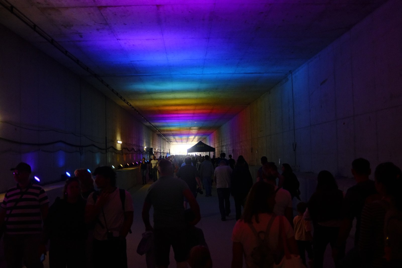 Silhouetted visitors in a hall lit in rainbow colours