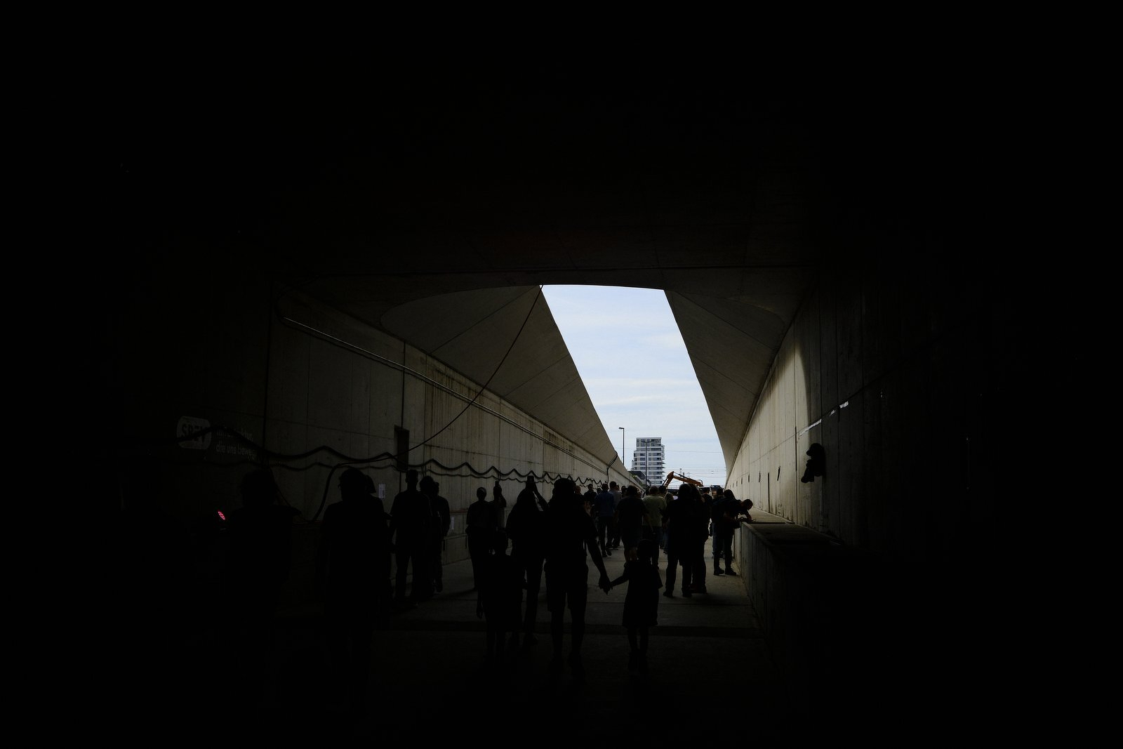 Silhouetted visitors at the tunnel mouth, a tower in the distance